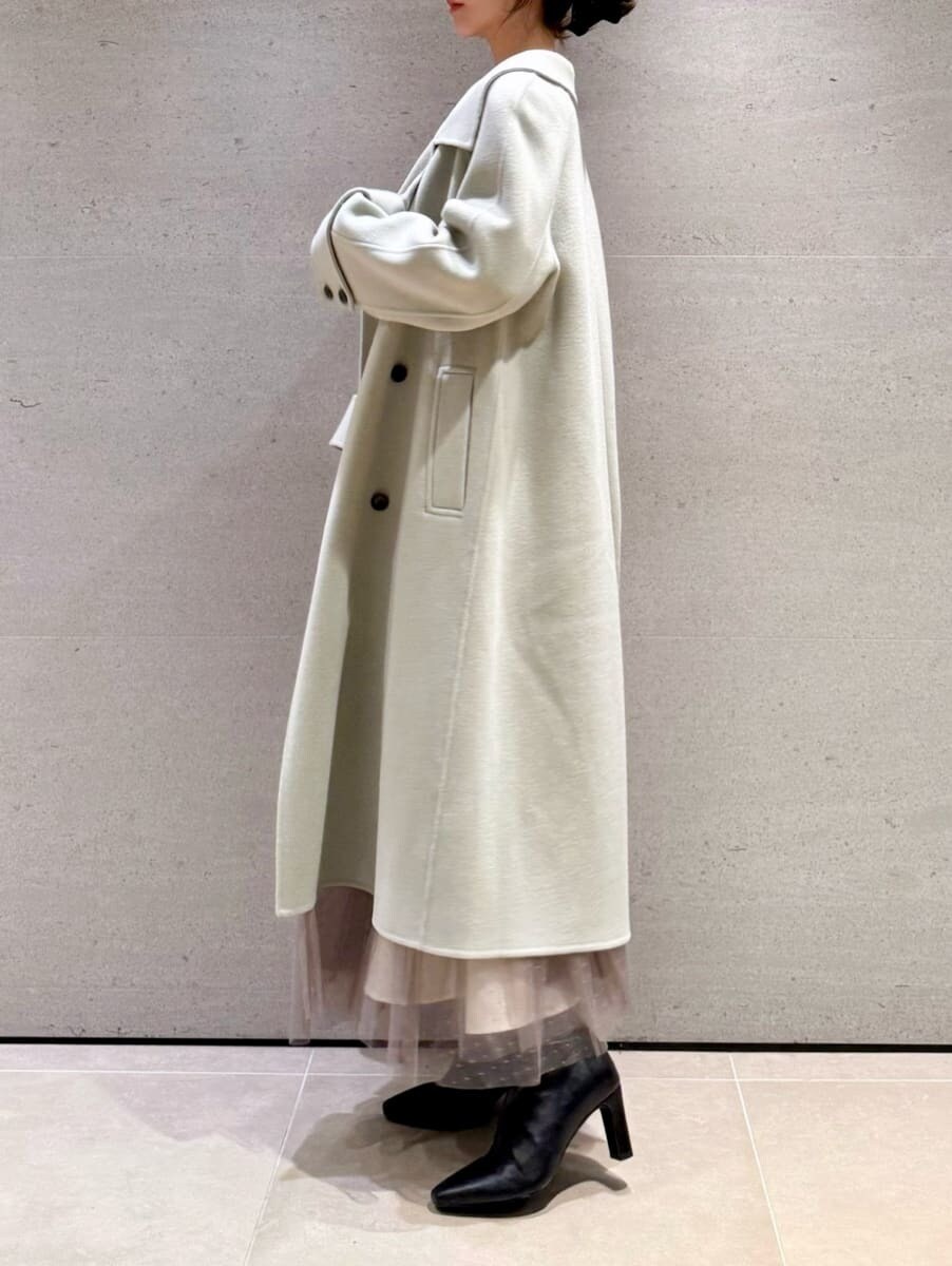 ブラック系のブーツ、ホワイト系のワンピース、グリーン系のチェスターコートを着用したレディースの秋コーディネートの2枚目の写真