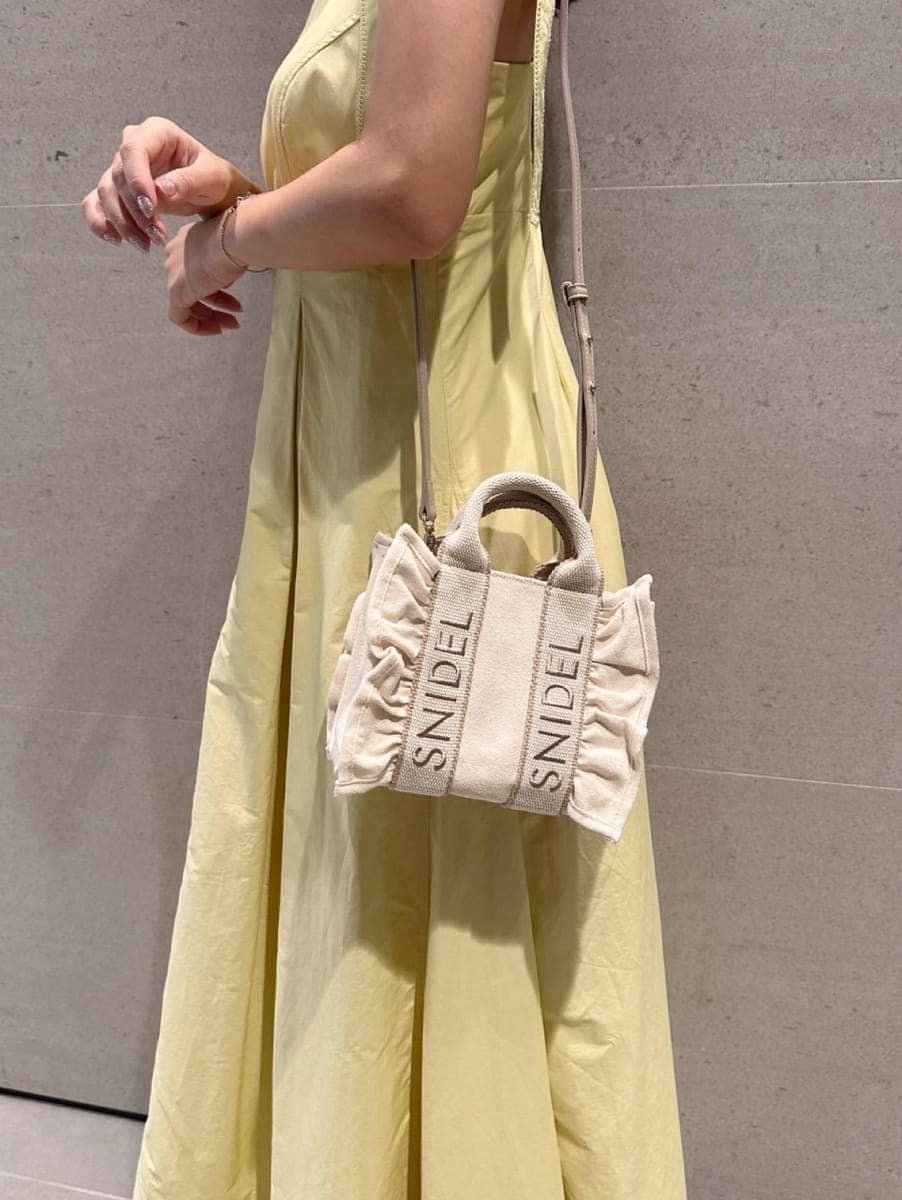 イエロー系のワンピース、ベージュ系のショルダーバッグ、ブラウン系のサンダルを着用したレディースの夏コーディネートの4枚目の写真