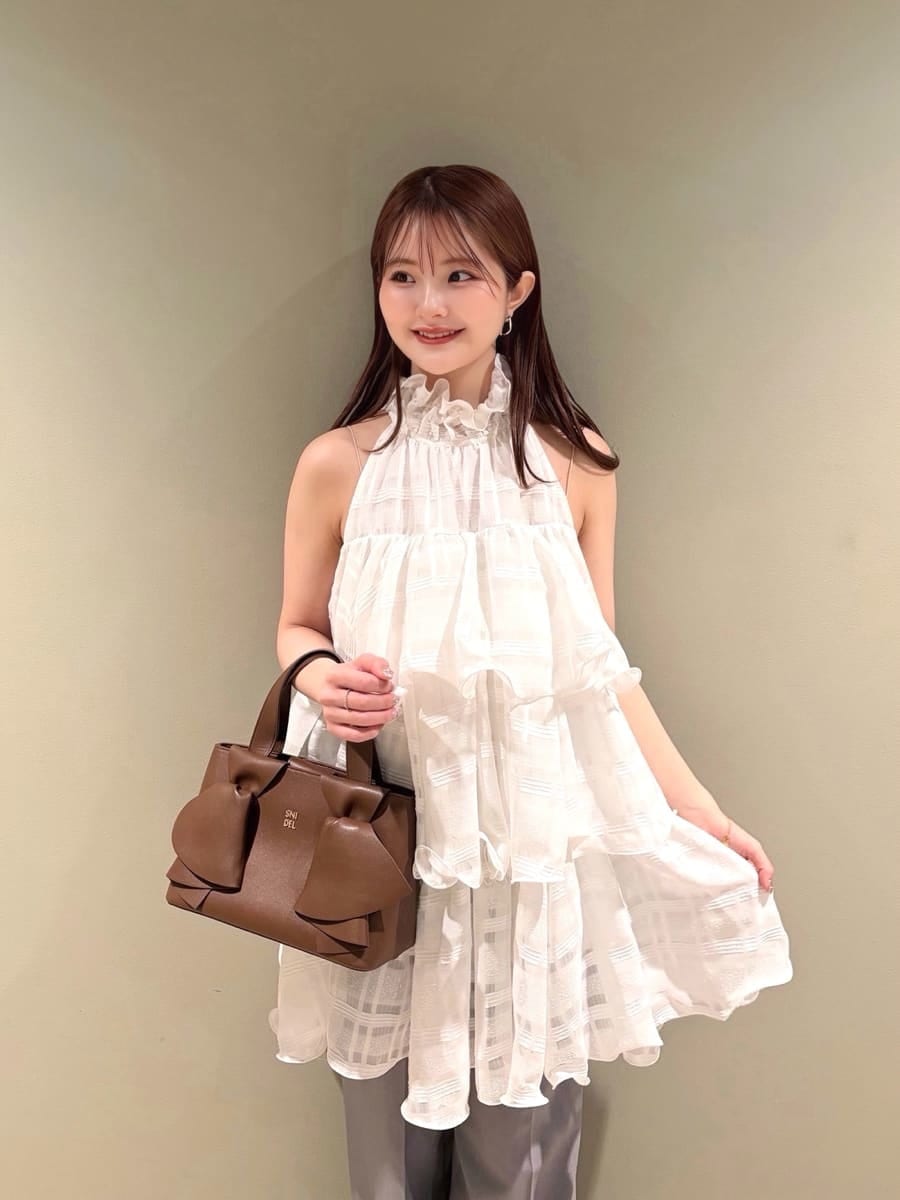 グレー系のスラックス、ホワイト系のワンピース、ブラウン系のパンプスを着用したレディースの春コーディネートの2枚目の写真