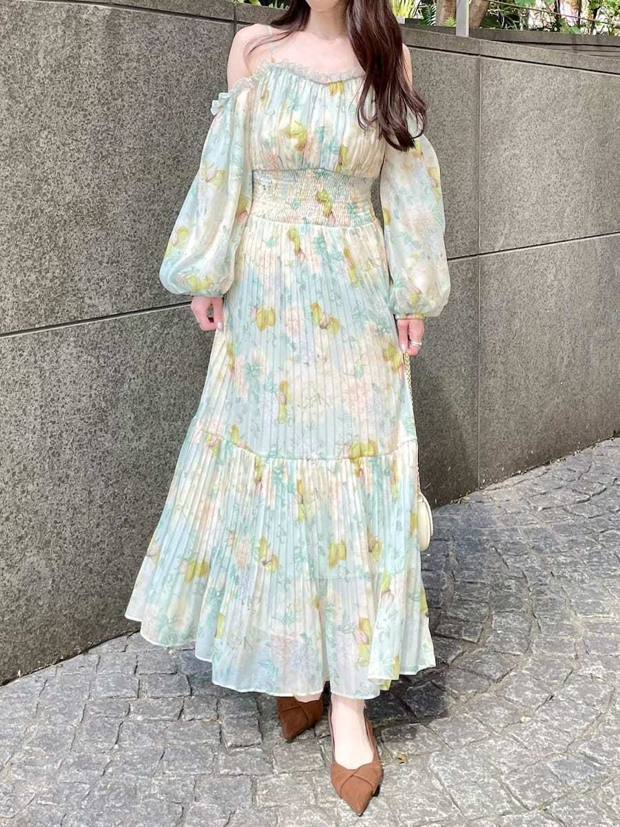 グリーン系のワンピース、ブラウン系のパンプス、ホワイト系のショルダーバッグを着用したレディースの春コーディネートの2枚目の写真