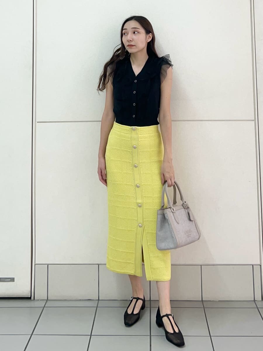 ブラック系のニット/セーター、イエロー系のスカート、ピンク系のハンドバッグを着用したレディースの夏コーディネートの2枚目の写真