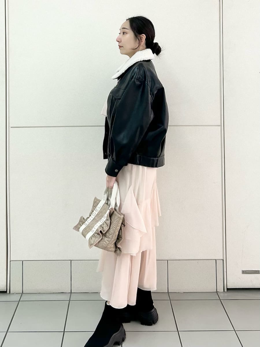 ベージュ系のハンドバッグ、ブラック系のブルゾン、ピンク系のワンピースを着用したレディースの冬コーディネートの3枚目の写真