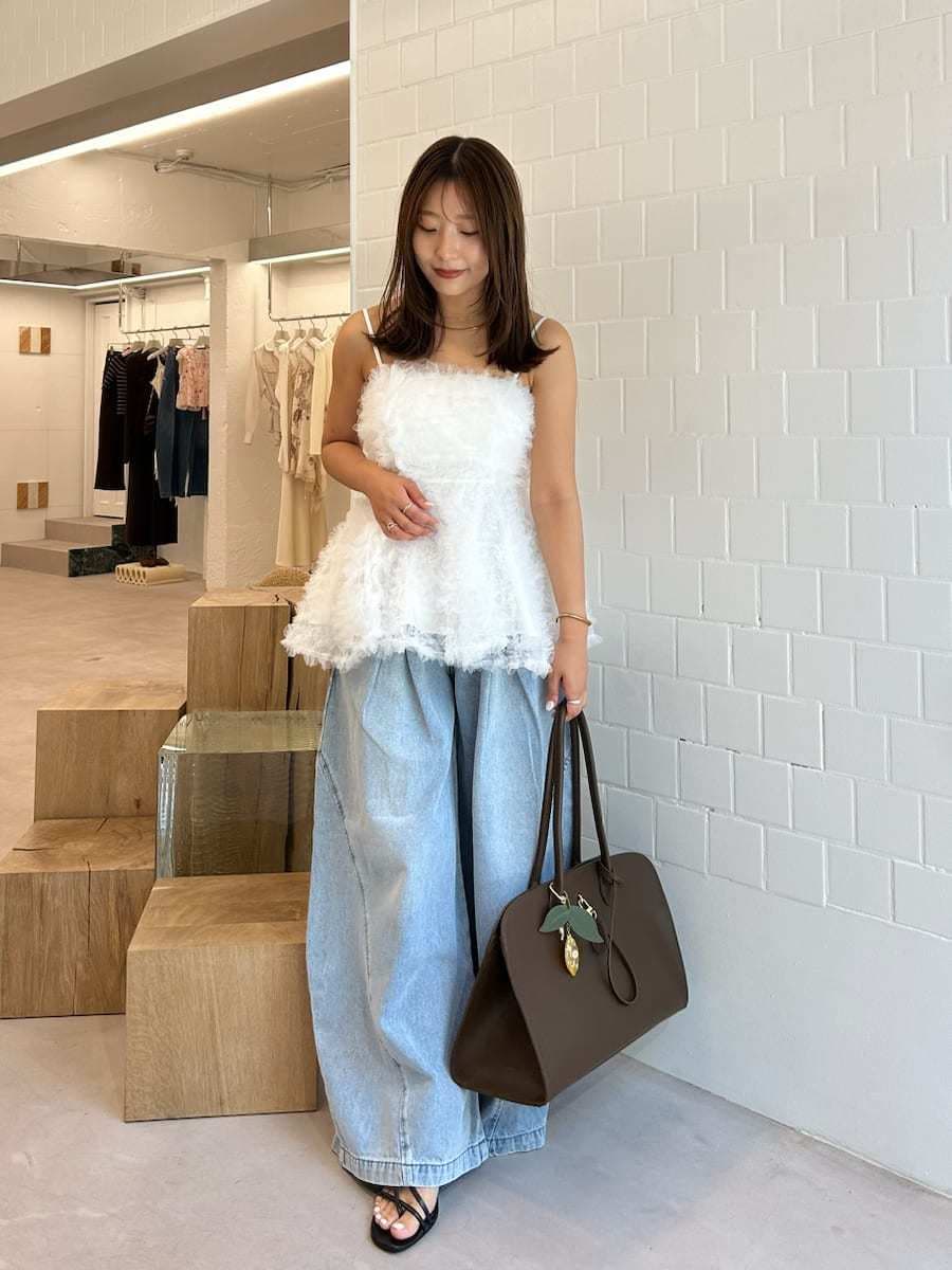 ブラック系のサンダル、ブルー系のデニムパンツ、ブラウン系のトートバッグを着用したレディースの夏コーディネートの2枚目の写真