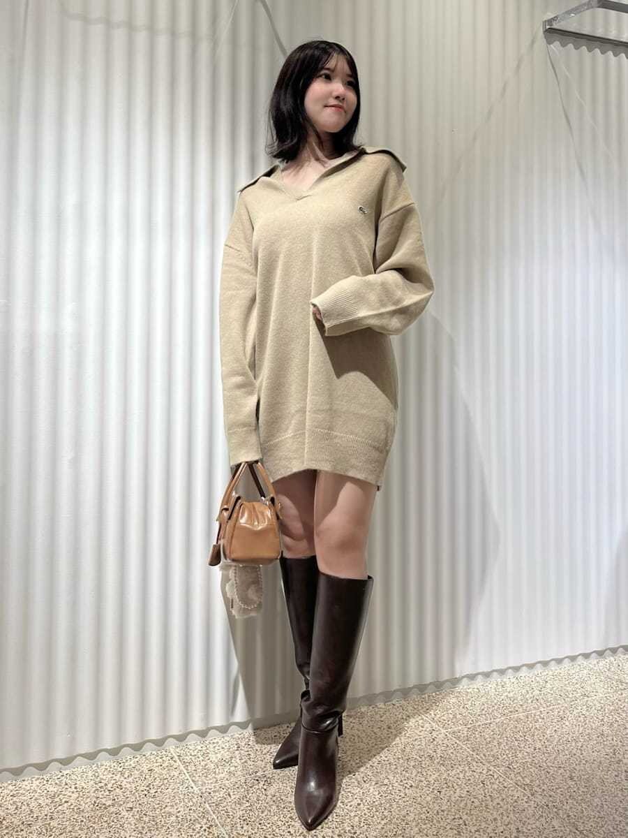 ホワイト系のダウンジャケット/コート、ブラウン系のブーツ、イエロー系のボストンバッグを着用したレディースの秋コーディネートの3枚目の写真