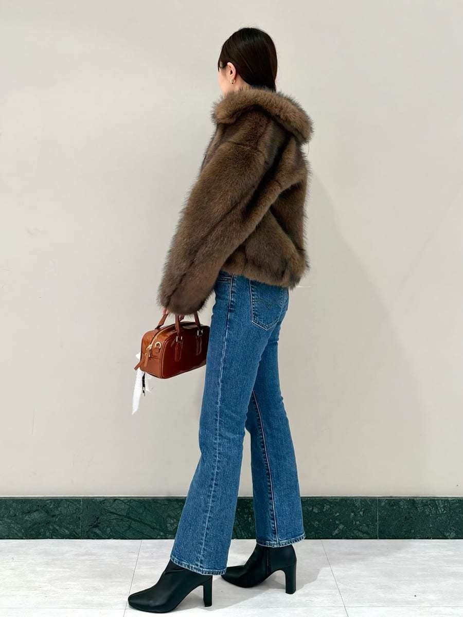 ブラウン系のチェスターコート、ブラック系のニット/セーター、ブルー系のデニムパンツを着用したレディースの秋コーディネートの2枚目の写真