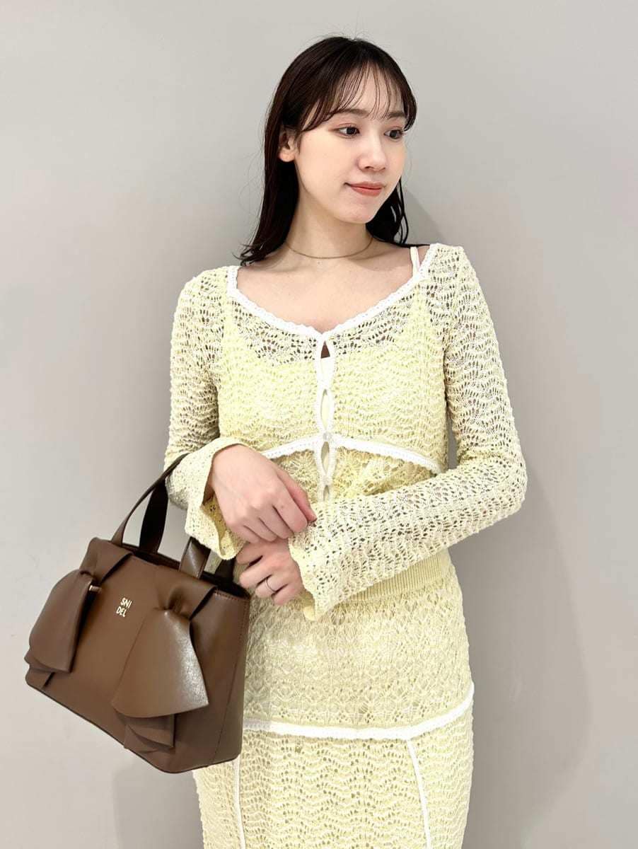 イエロー系のスカート、ブラウン系のパンプス、ブラウン系のハンドバッグを着用したレディースの春コーディネートの2枚目の写真