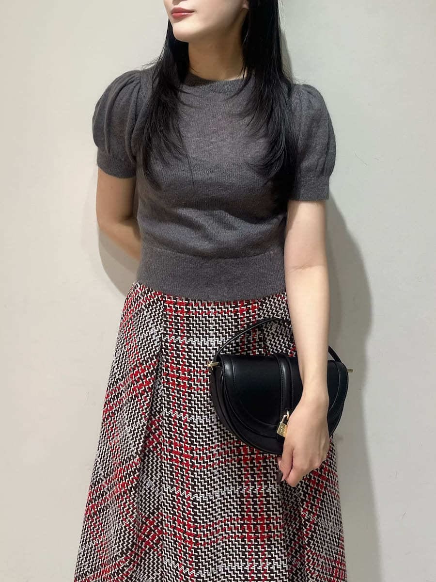 グレー系のニット/セーター、レッド系のスカート、ブラック系のハンドバッグを着用したレディースの秋コーディネートの4枚目の写真