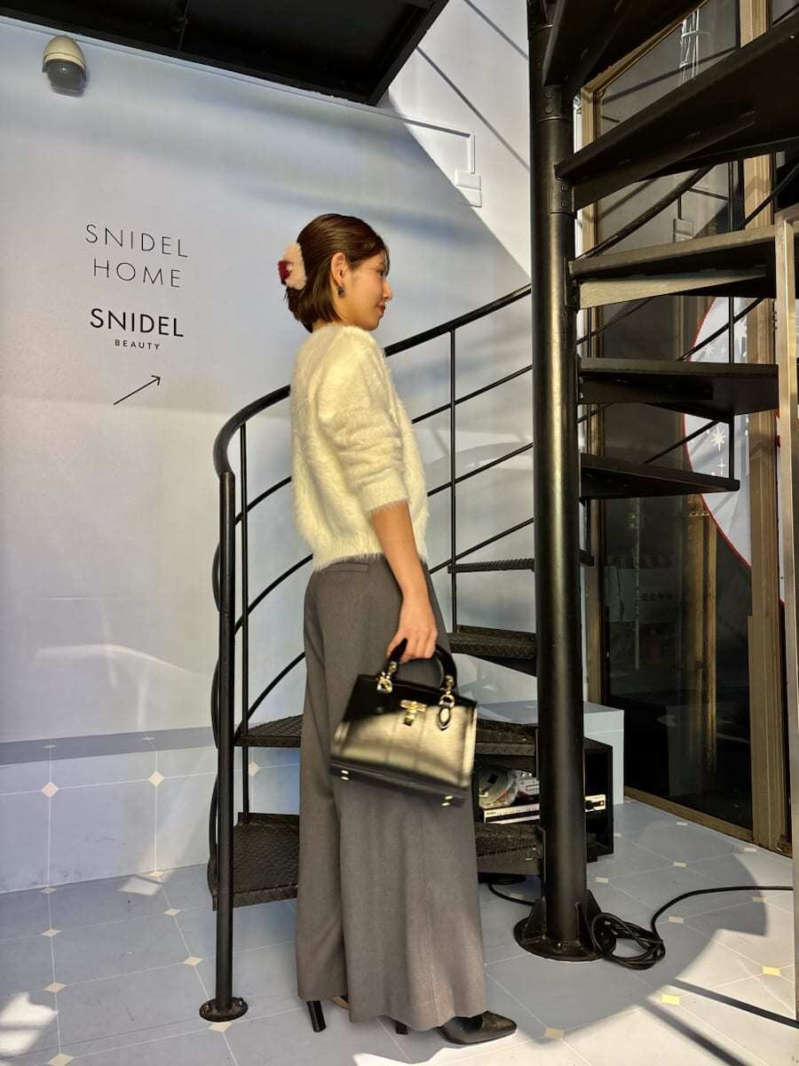 ブラック系のブーツ、ホワイト系のニット/セーター、ブラック系のハンドバッグを着用したレディースの秋コーディネートの3枚目の写真