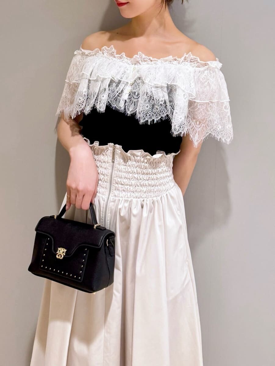 ブラック系のニット/セーター、ホワイト系のスカート、ブラック系のショルダーバッグを着用したレディースの夏コーディネートの3枚目の写真