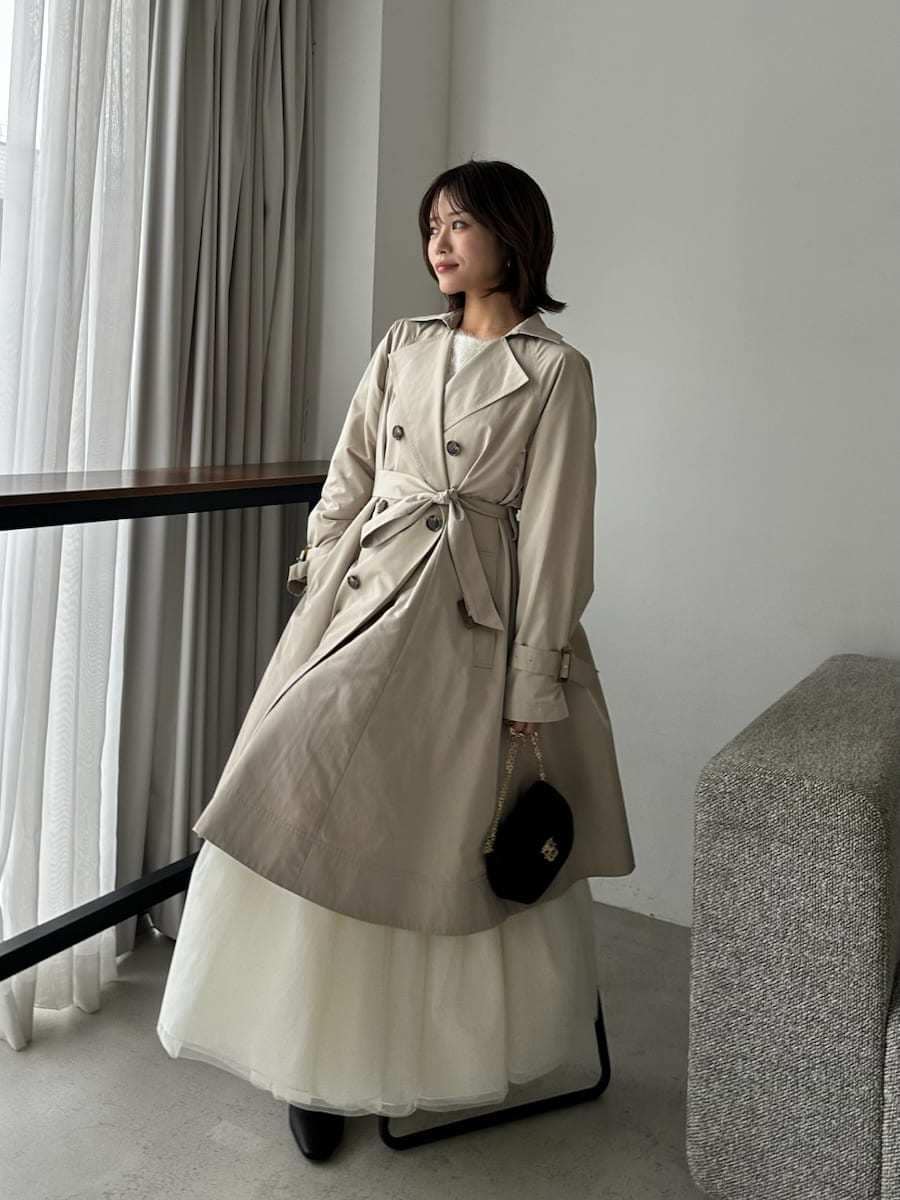 ベージュ系のトレンチコート、ベージュ系のワンピース、ブラック系のショルダーバッグを着用したレディースの春コーディネートの6枚目の写真