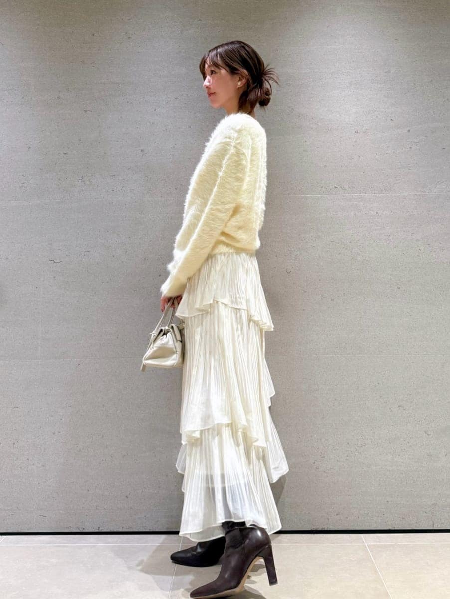 ブラウン系のブーツ、ホワイト系のスカート、イエロー系のニット/セーターを着用したレディースの秋コーディネートの2枚目の写真