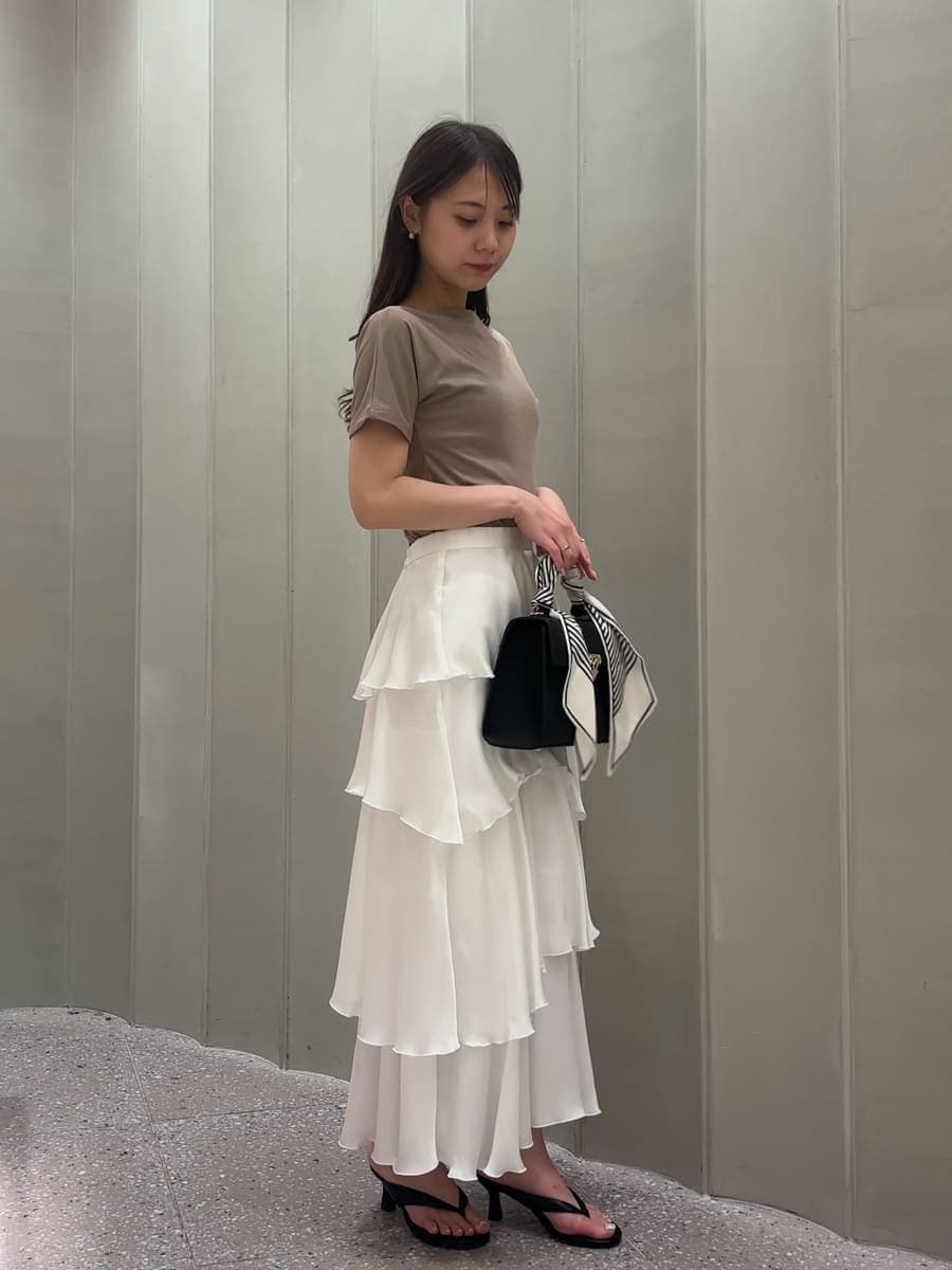 ブラック系のハンドバッグ、ホワイト系のスカート、ベージュ系のTシャツ/カットソーを着用したレディースの夏コーディネートの2枚目の写真