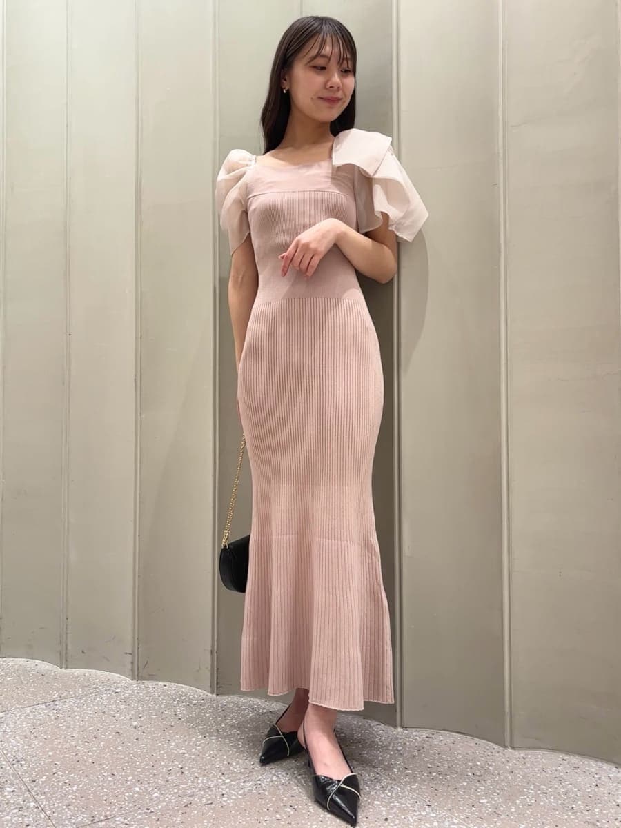 ピンク系のワンピース、ブラック系のパンプス、ブラック系のショルダーバッグを着用したレディースの春コーディネートの2枚目の写真