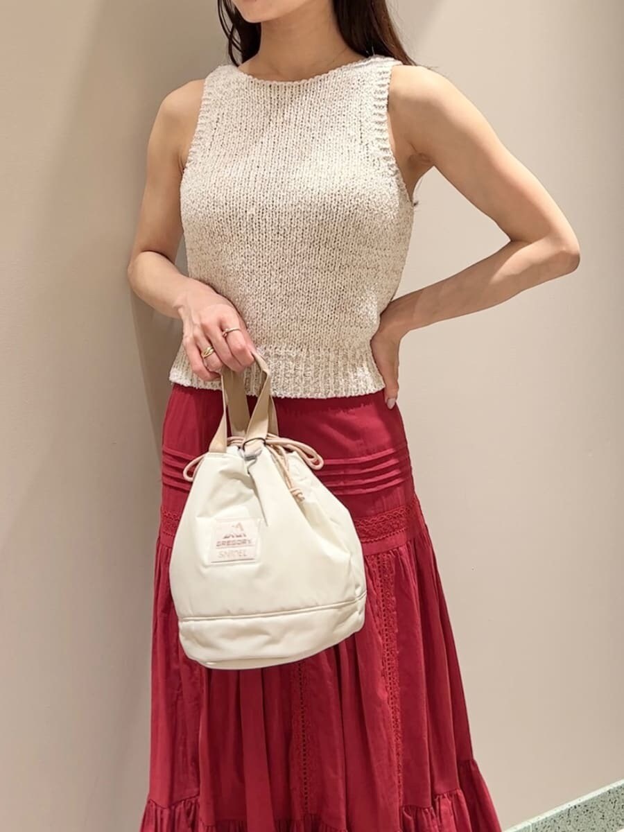ホワイト系のニット/セーター、レッド系のスカート、ベージュ系のハンドバッグを着用したレディースの夏コーディネートの4枚目の写真