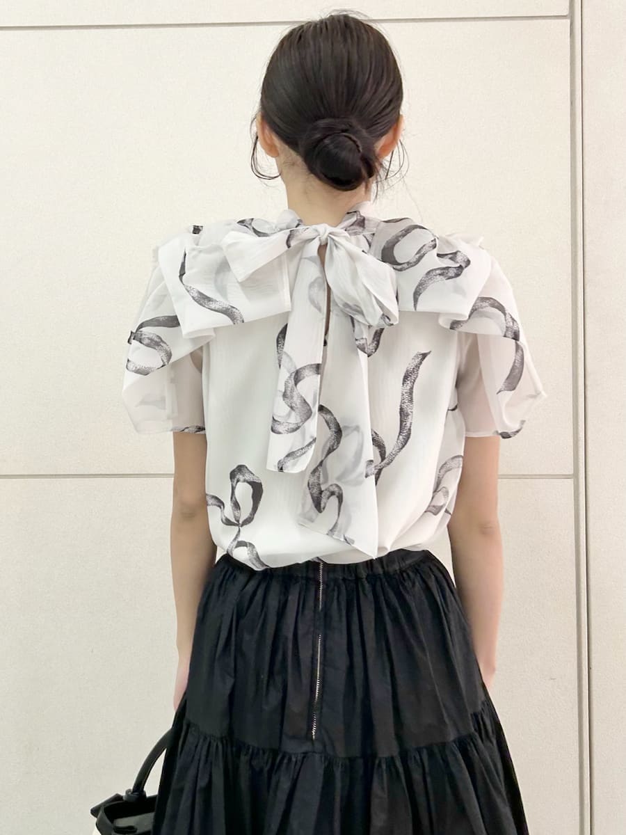 ブラック系のスカート、ブラック系のパンプス、ホワイト系のハンドバッグを着用したレディースの春コーディネートの7枚目の写真