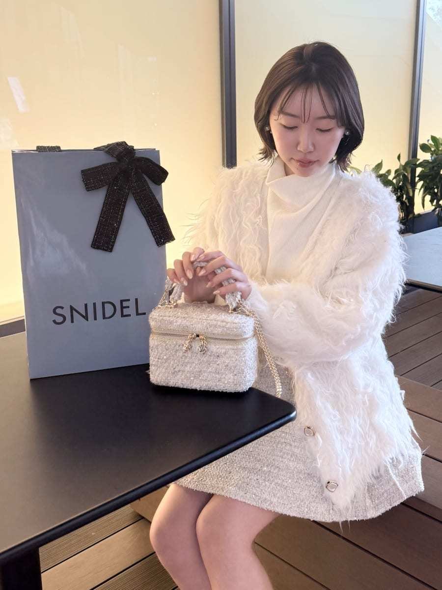 ホワイト系のスカート、ホワイト系のカーディガン/ボレロ、ホワイト系のハンドバッグを着用したレディースの冬コーディネートの10枚目の写真