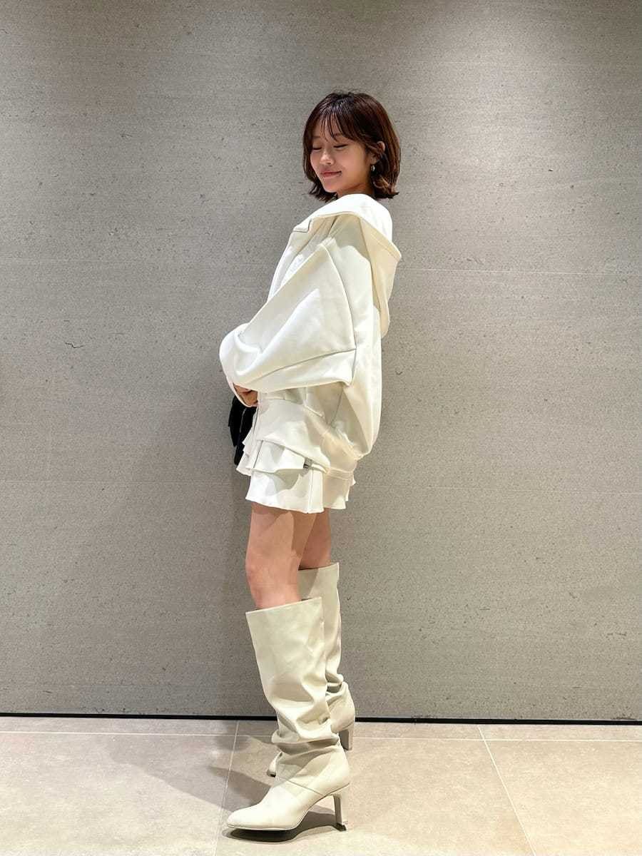 ホワイト系のパーカー、ホワイト系のブーツ、ブラック系のショルダーバッグを着用したレディースの冬コーディネートの4枚目の写真