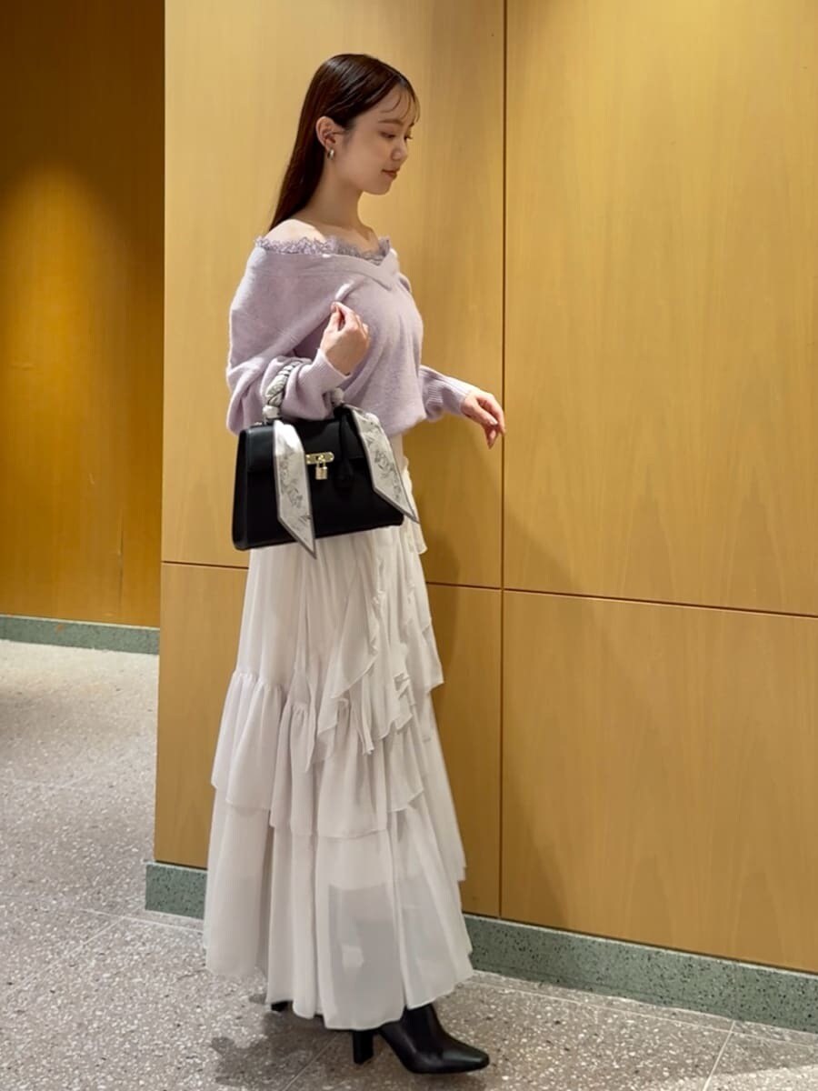 パープル系のニット/セーター、ホワイト系のスカート、ブラック系のブーツを着用したレディースの秋コーディネートの2枚目の写真