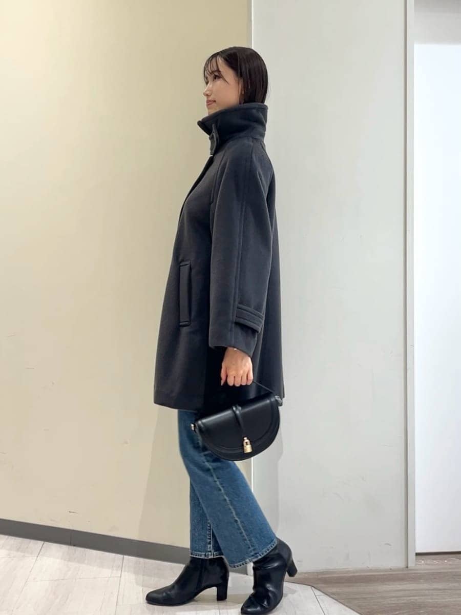 グレー系のステンカラーコート、レッド系のニット/セーター、ブルー系のデニムパンツを着用したレディースの秋コーディネートの9枚目の写真