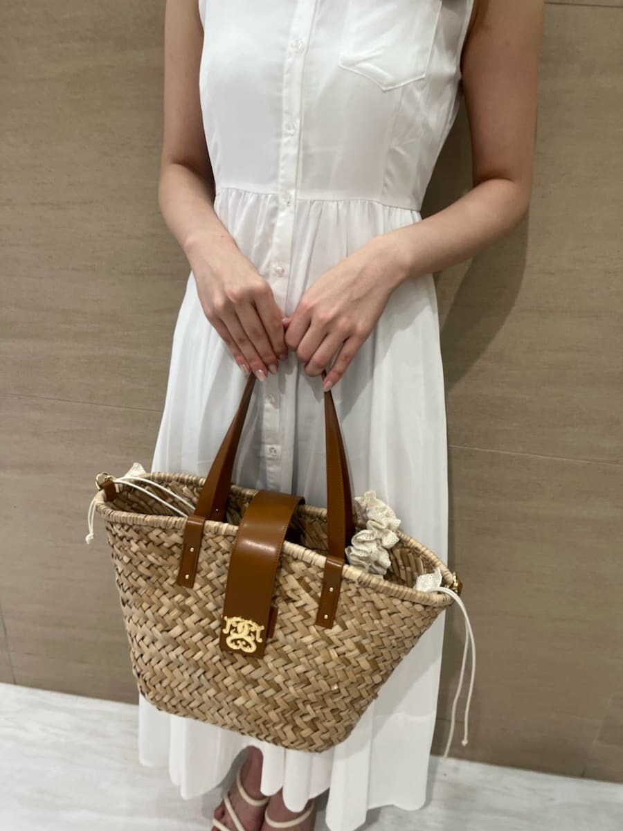 ホワイト系のワンピース、ブラウン系のかごバッグ、ホワイト系のパンプスを着用したレディースの夏コーディネートの5枚目の写真