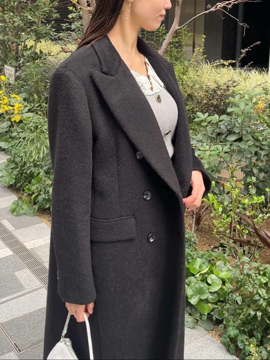 ブラック系のチェスターコート、グレー系のワンピースを着用したレディースの冬コーディネートの4枚目の写真