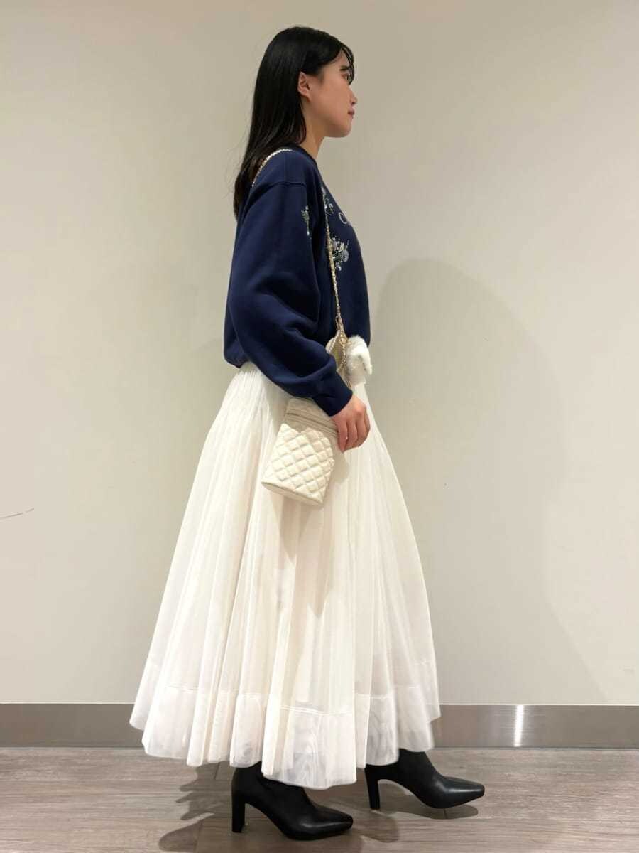 ブルー系のスウェット、ホワイト系のスカート、ブラック系のブーツを着用したレディースの秋コーディネートの2枚目の写真