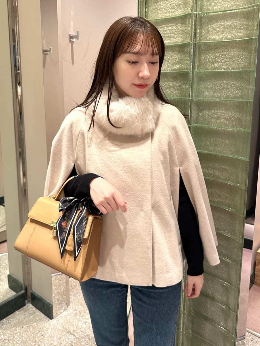 ホワイト系のチェスターコート、ブルー系のデニムパンツを着用したレディースの秋コーディネートの2枚目の写真