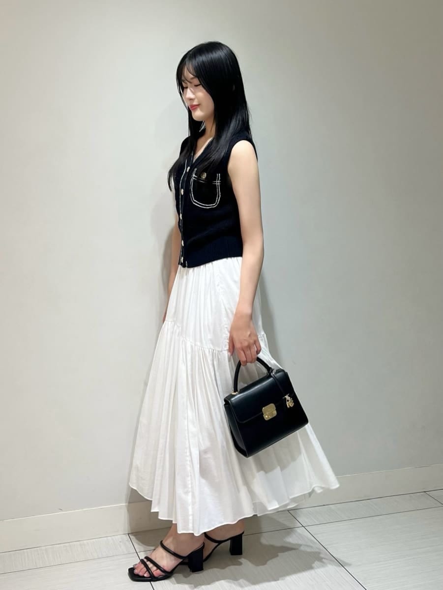 ブルー系のニット/セーター、ホワイト系のスカート、ブラック系のショルダーバッグを着用したレディースの夏コーディネートの2枚目の写真