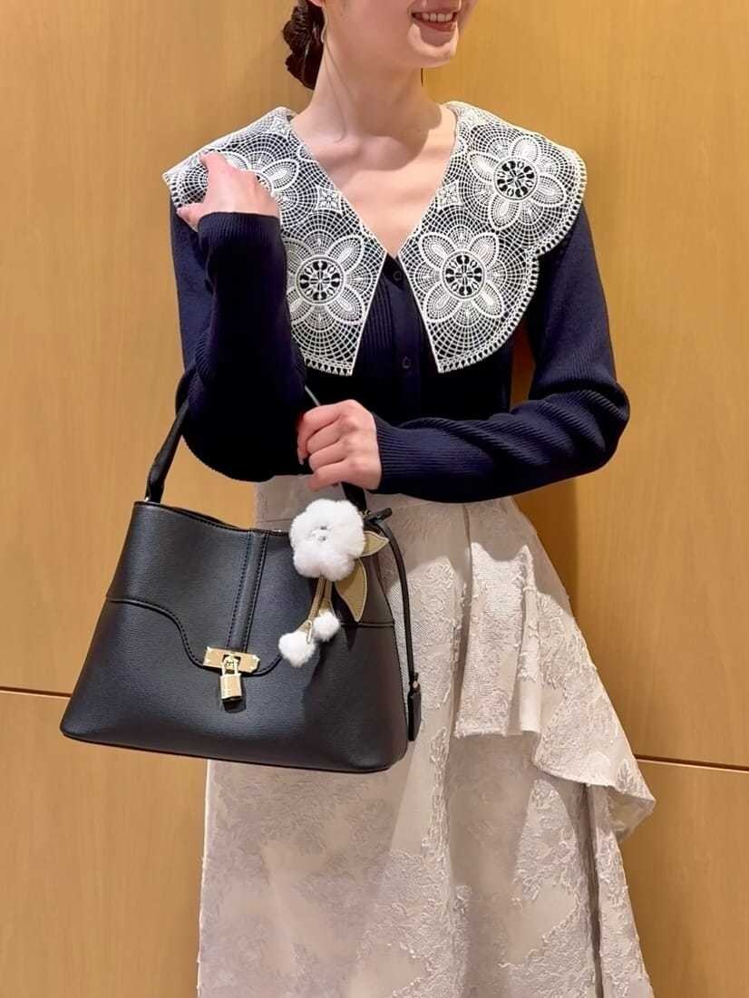 ブルー系のニット/セーター、ブラック系のハンドバッグ、ホワイト系のチャームを着用したレディースの冬コーディネートの7枚目の写真