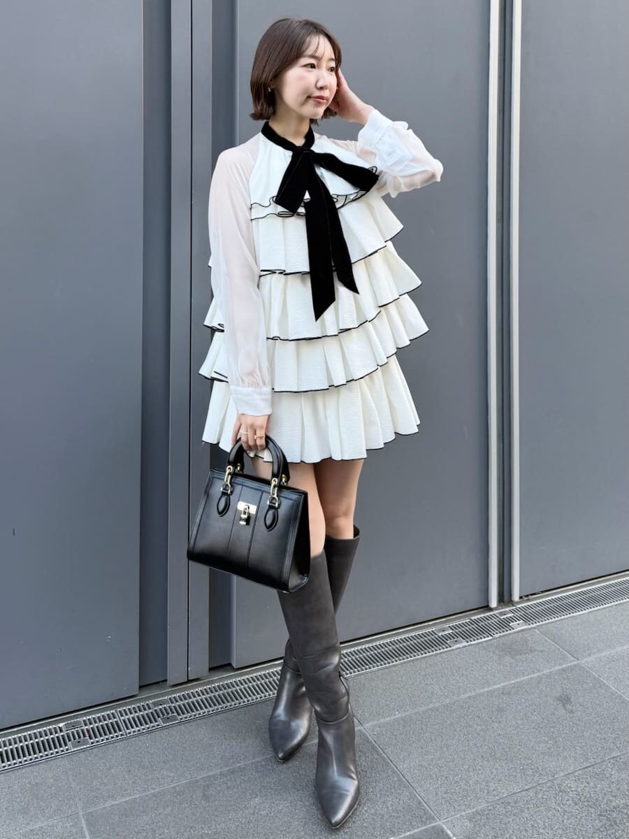 ホワイト系のドレス、ブラック系のハンドバッグを着用したレディースの冬コーディネートの6枚目の写真
