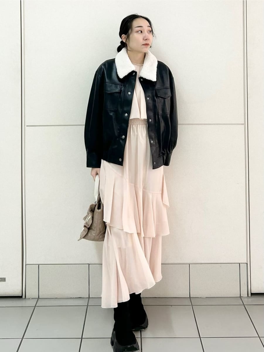 ベージュ系のハンドバッグ、ブラック系のブルゾン、ピンク系のワンピースを着用したレディースの冬コーディネートの2枚目の写真
