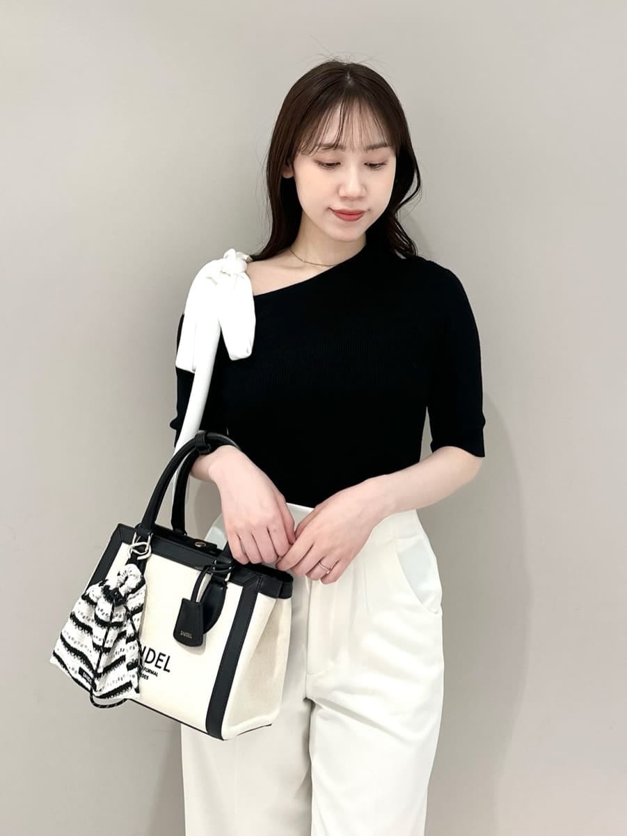 ホワイト系のスラックス、ホワイト系のハンドバッグ、ブラック系のパンプスを着用したレディースの春コーディネートの2枚目の写真