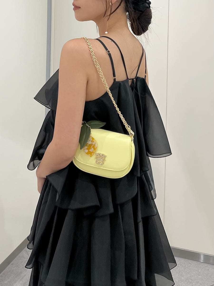イエロー系のショルダーバッグ、イエロー系のカーディガン/ボレロ、ブラック系のドレスを着用したレディースの夏コーディネートの8枚目の写真