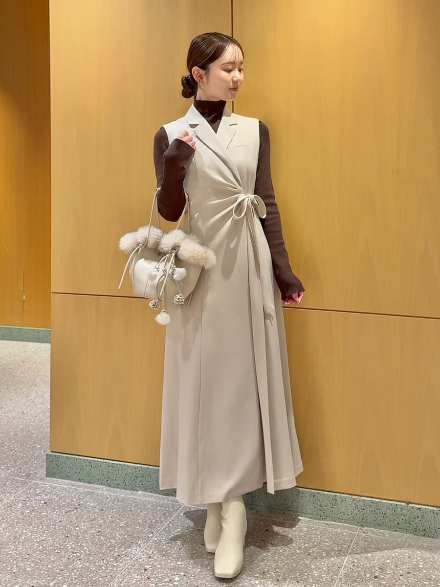 ピンク系のステンカラーコート、ベージュ系のワンピース、ブラウン系のニット/セーターを着用したレディースの秋コーディネートの4枚目の写真