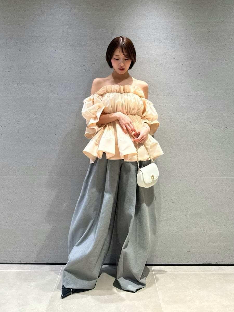 グレー系のデニムパンツ、オレンジ系のその他トップス、ブラック系のパンプスを着用したレディースの春コーディネートの2枚目の写真