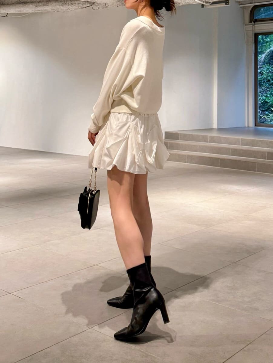 ホワイト系のキャミソール、ブラック系のブーツ、ブラウン系のステンカラーコートを着用したレディースの秋コーディネートの4枚目の写真