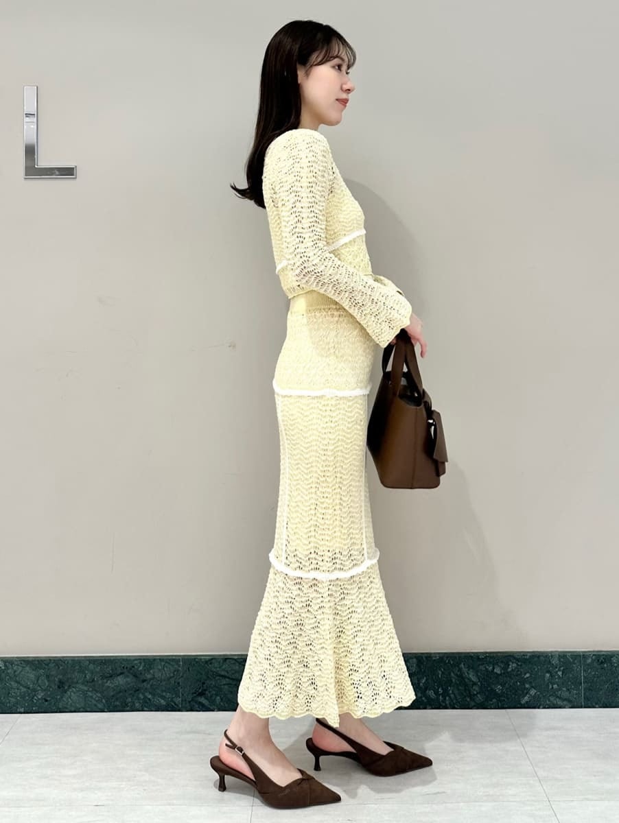 イエロー系のスカート、ブラウン系のパンプス、ブラウン系のハンドバッグを着用したレディースの春コーディネートの4枚目の写真