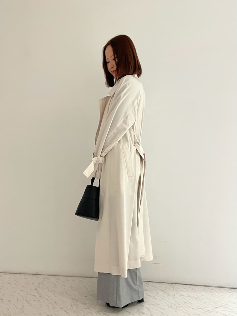 ブラック系のショルダーバッグ、ブラック系のニット/セーター、ホワイト系のトレンチコートを着用したレディースの冬コーディネートの2枚目の写真