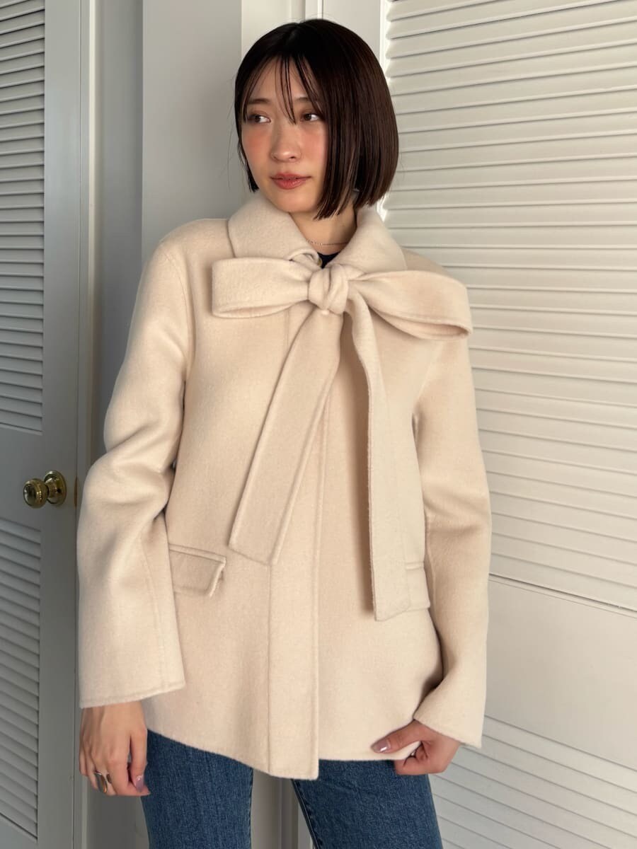 ブルー系のデニムパンツ、ブラウン系のハンドバッグを着用したレディースの秋コーディネートの3枚目の写真