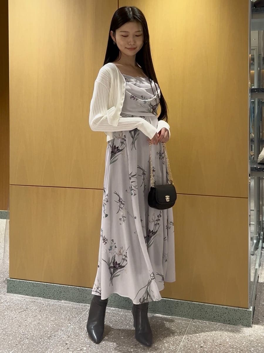 グレー系のブーツ、ホワイト系のカーディガン/ボレロ、パープル系のワンピースを着用したレディースの冬コーディネートの3枚目の写真