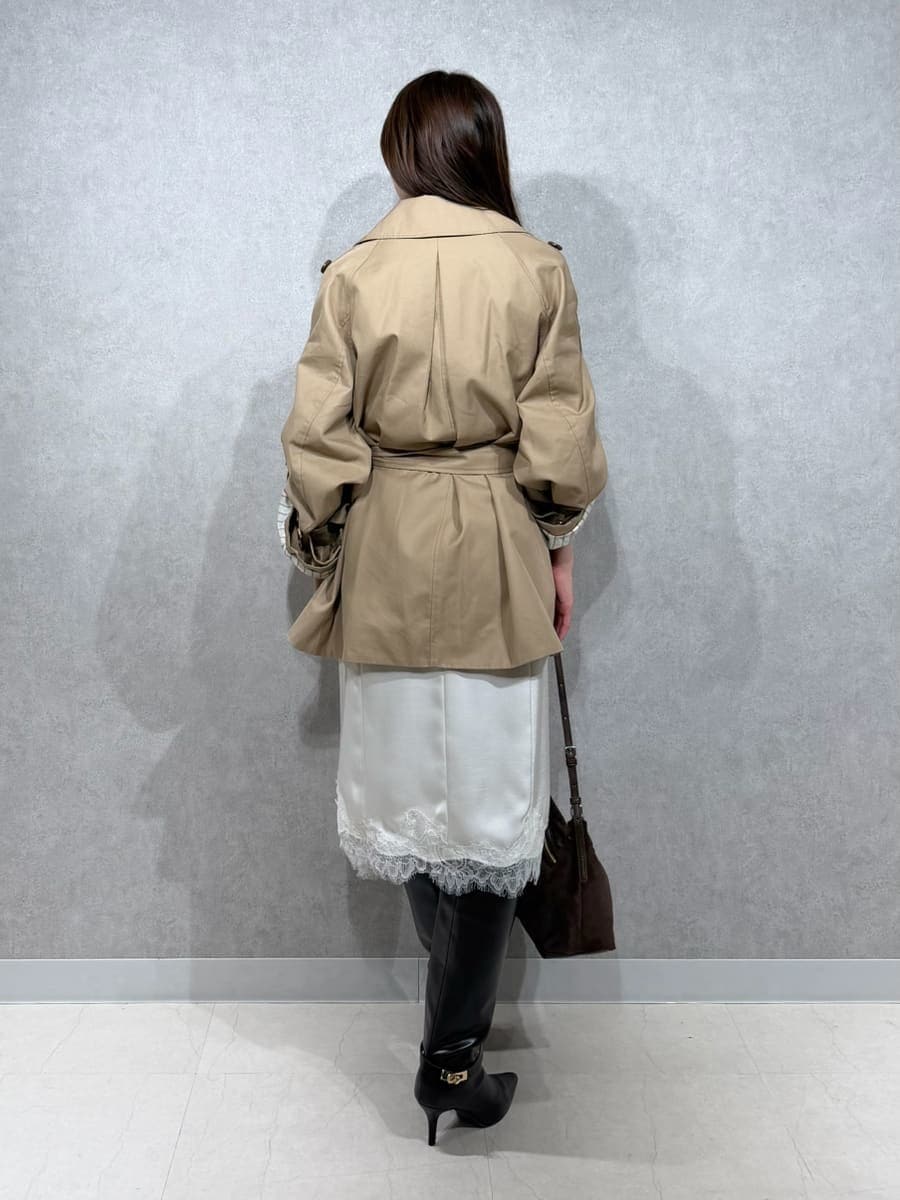ベージュ系のトレンチコート、ホワイト系のスカート、ブラウン系のTシャツ/カットソーを着用したレディースの秋コーディネートの3枚目の写真