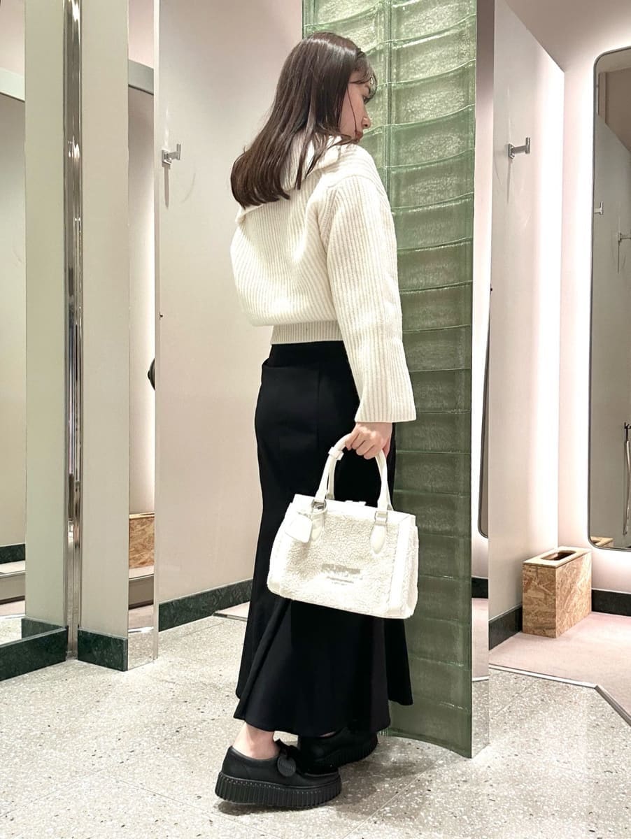 ホワイト系のニット/セーター、ブラック系のスカート、ホワイト系のハンドバッグを着用したレディースの秋コーディネートの3枚目の写真