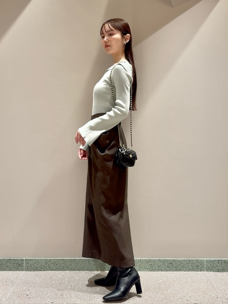 グリーン系のニット/セーター、ブラウン系のスカート、ブラック系のブーツを着用したレディースの秋コーディネートの2枚目の写真