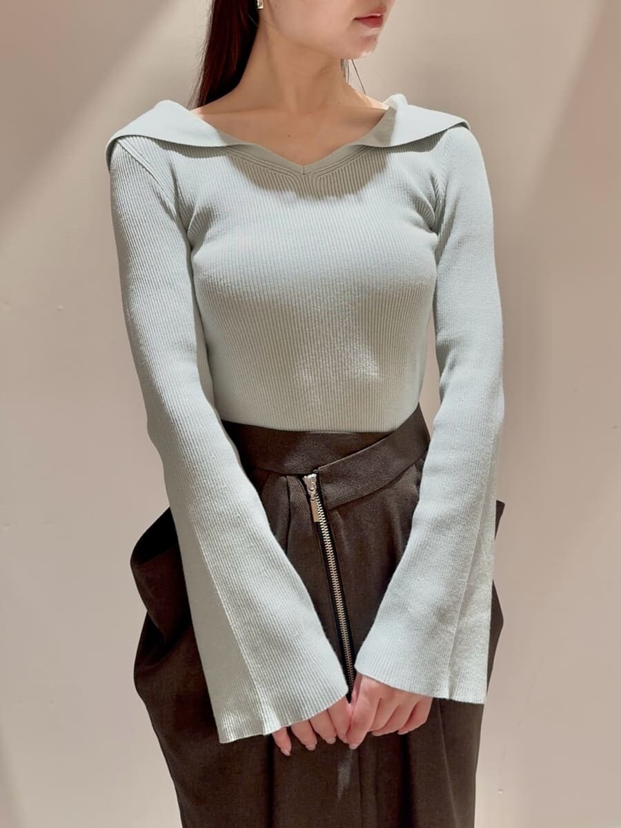 グリーン系のニット/セーター、ブラウン系のスカート、ブラック系のブーツを着用したレディースの秋コーディネートの4枚目の写真