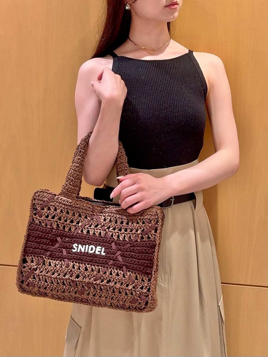 ベージュ系のスカート、ブラック系のニット/セーター、ブラウン系のトートバッグを着用したレディースの夏コーディネートの5枚目の写真