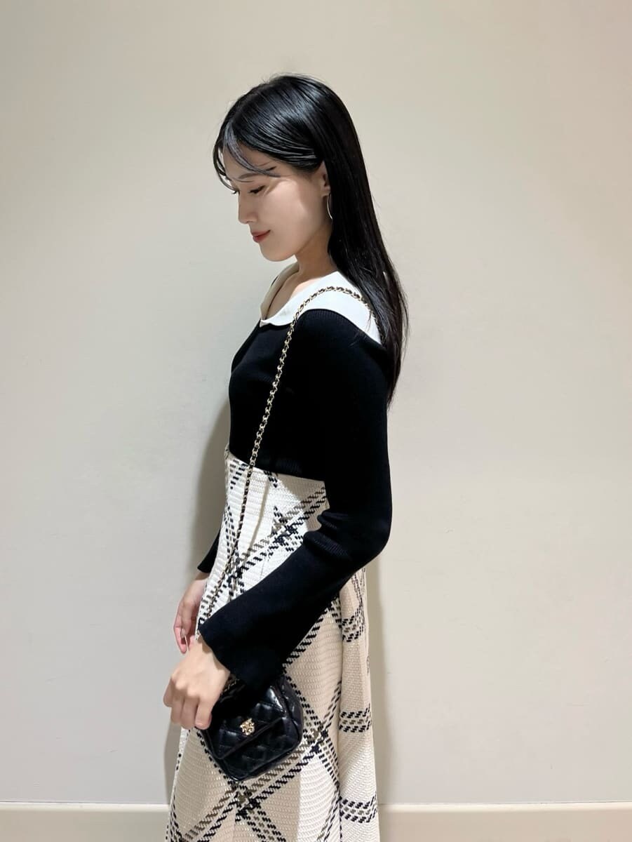 ブラック系のニット/セーター、ホワイト系のスカート、ブラック系のショルダーバッグを着用したレディースの秋コーディネートの4枚目の写真