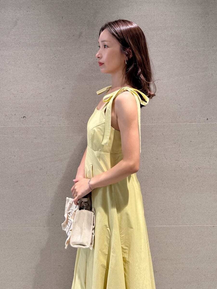 イエロー系のワンピース、ベージュ系のショルダーバッグ、ブラウン系のサンダルを着用したレディースの夏コーディネートの2枚目の写真
