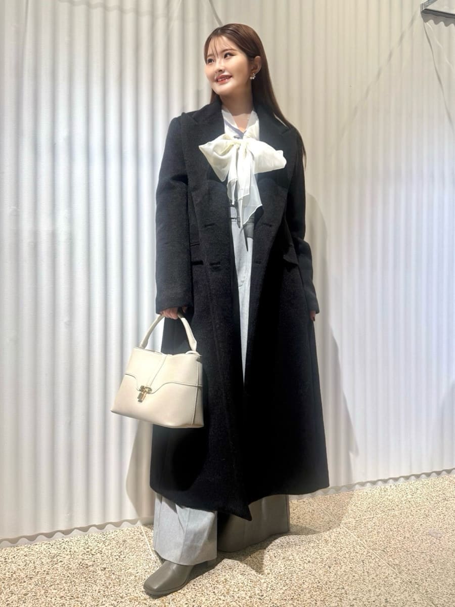 ブラック系のチェスターコート、ブルー系のニット/セーター、ホワイト系のハンドバッグを着用したレディースの冬コーディネートの3枚目の写真