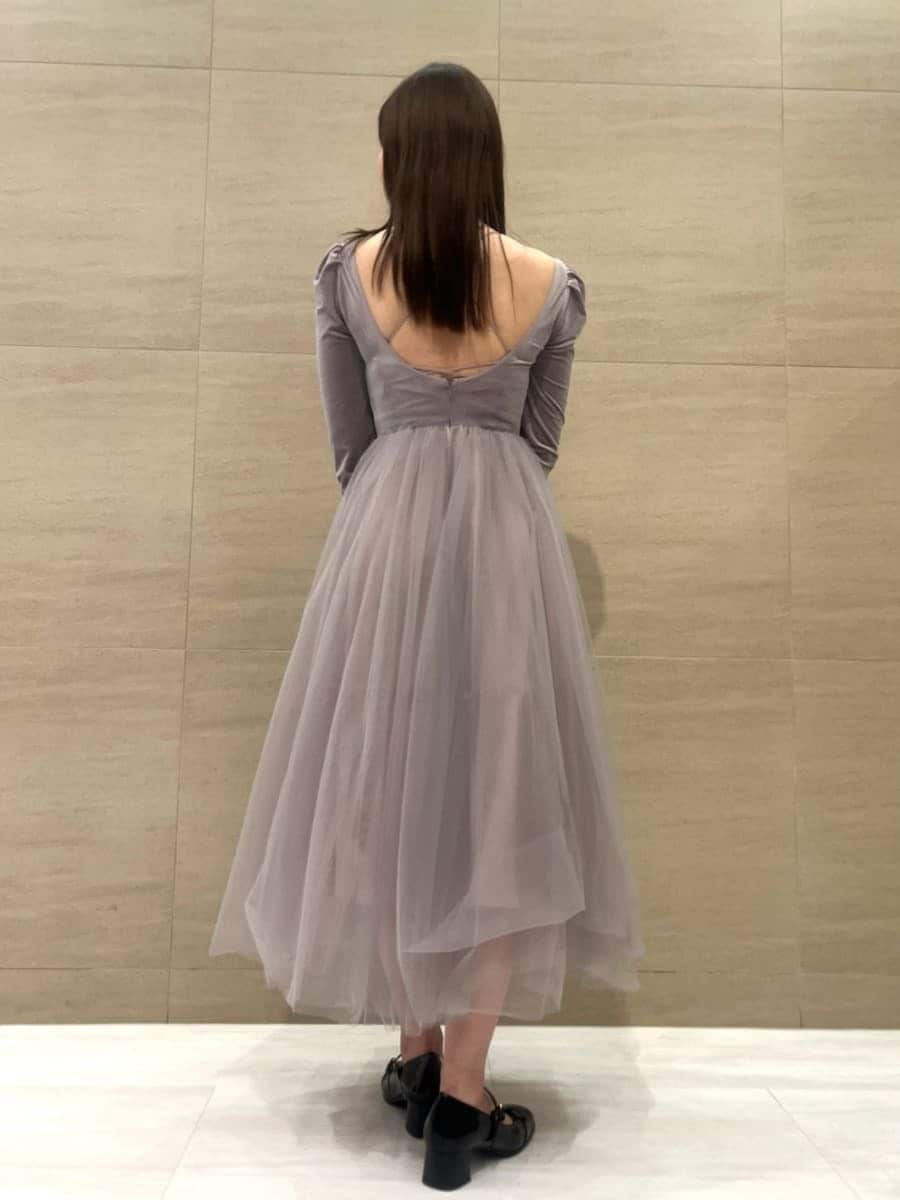 パープル系のワンピース、ブラック系のパンプス、ブラック系のショルダーバッグを着用したレディースの秋コーディネートの3枚目の写真