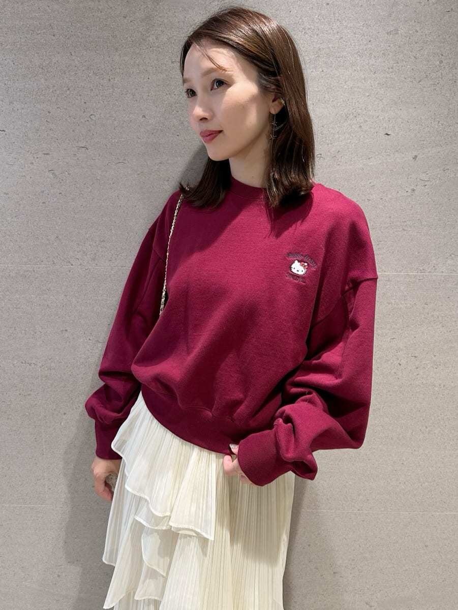 レッド系のスウェット、ホワイト系のスカート、ホワイト系のショルダーバッグを着用したレディースの秋コーディネートの2枚目の写真